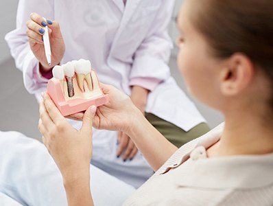 A woman holding a dental implant model