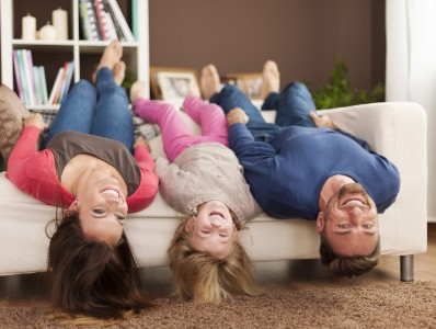 Parents and child upside down on couch smiling after family dentistry