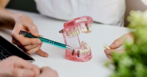 Dentist using model to explain dental implant removal